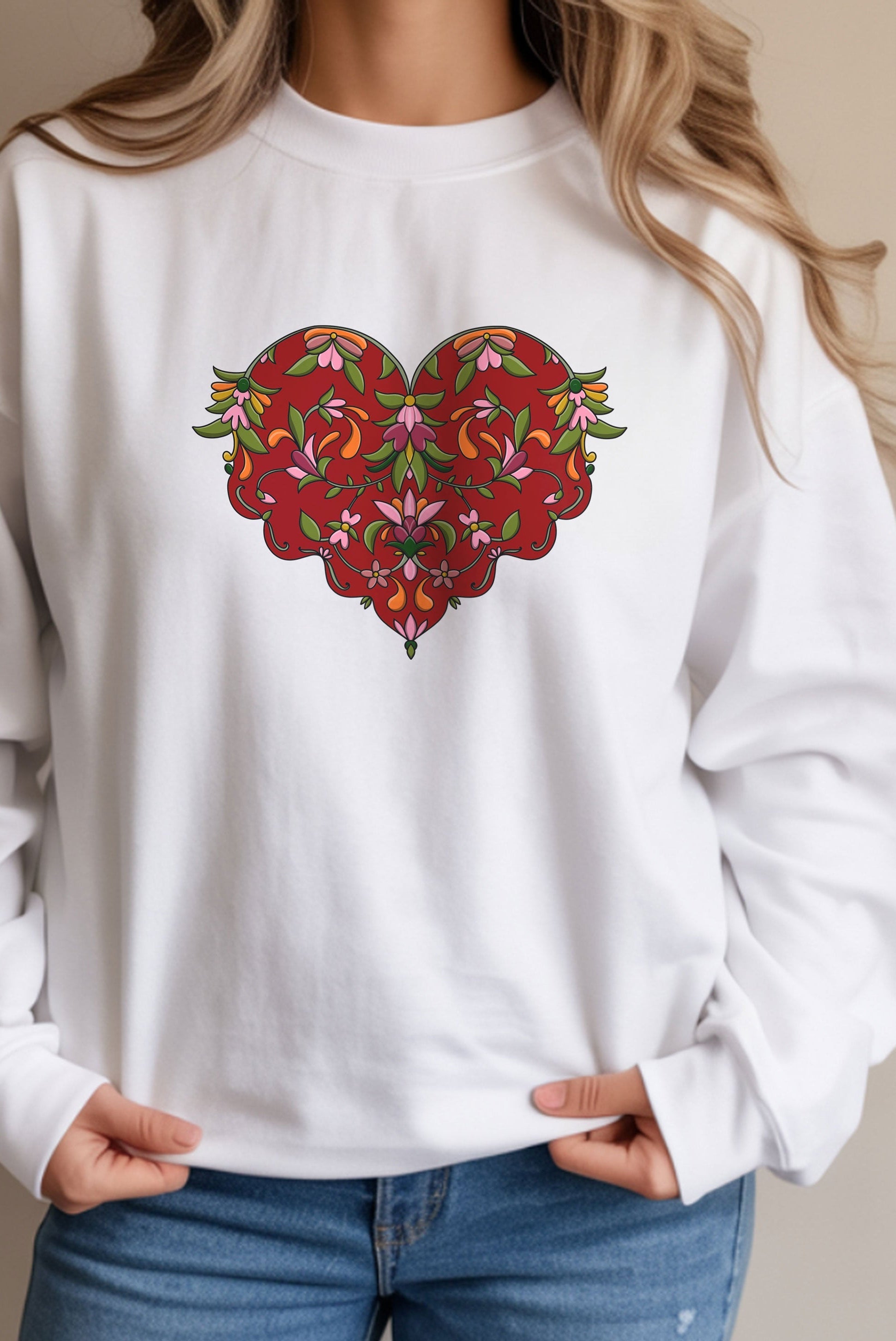 White sweatshirt with a colorful heart design worn by a person.